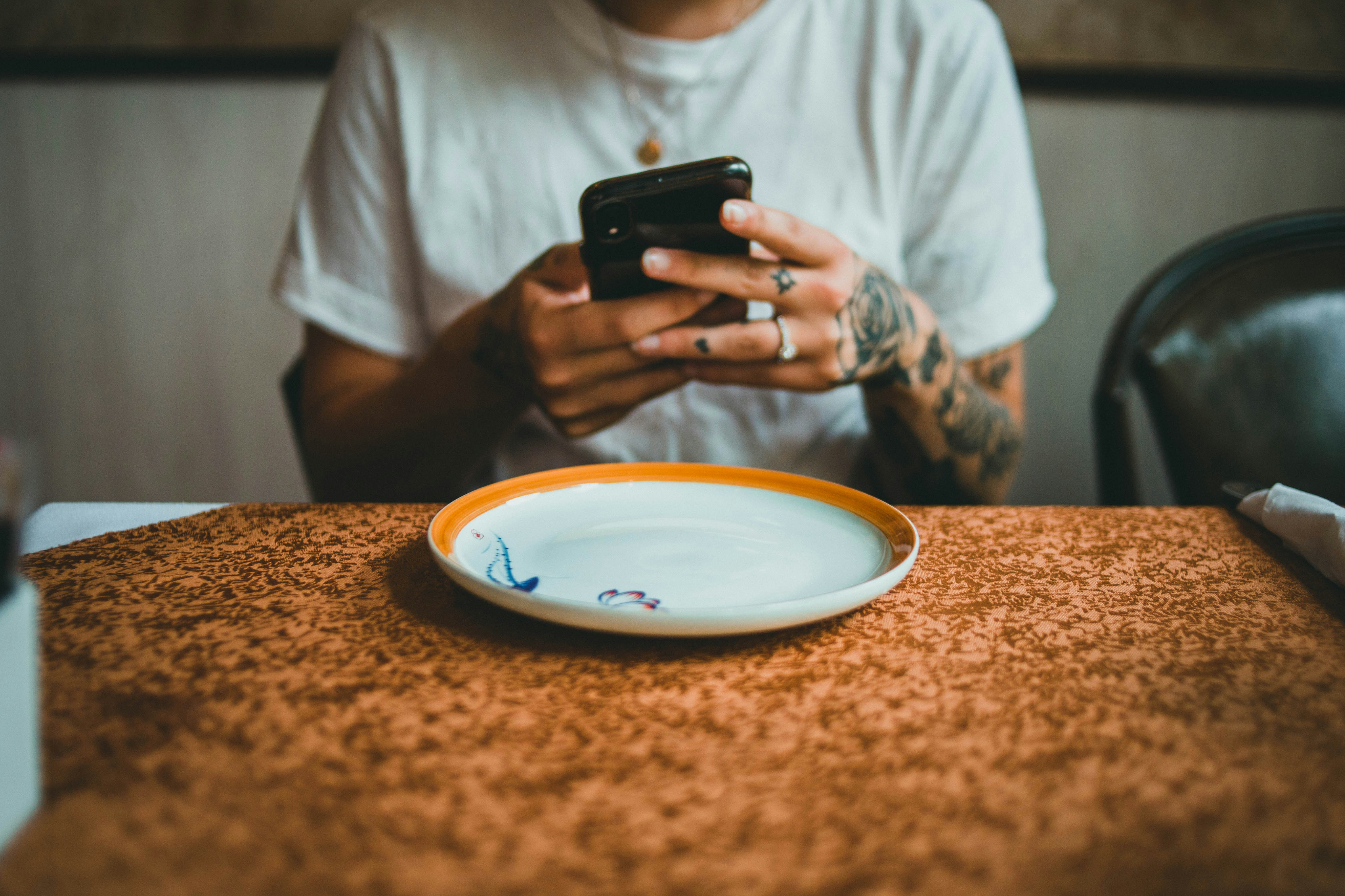 person in white crew neck t-shirt holding black smartphone